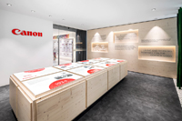 Bamboo poles, light wood and a table showcasing 8 milestones from the Canon history welcome visitors