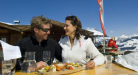 Paar vor Skihütte mit einer Brettljause