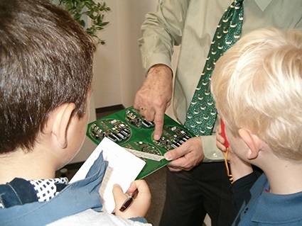 Unternehmer erklärt Kindern den Aufbau einer Leiterplatte Unternehmer erklärt Kindern den Aufbau einer Leiterplatte