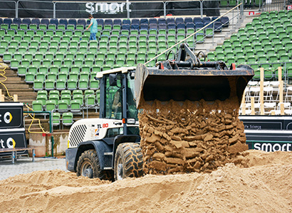 Ein Radlader aus dem HKL MIETPARK verteilt den besonderen Beach-Sand auf dem Center Court.