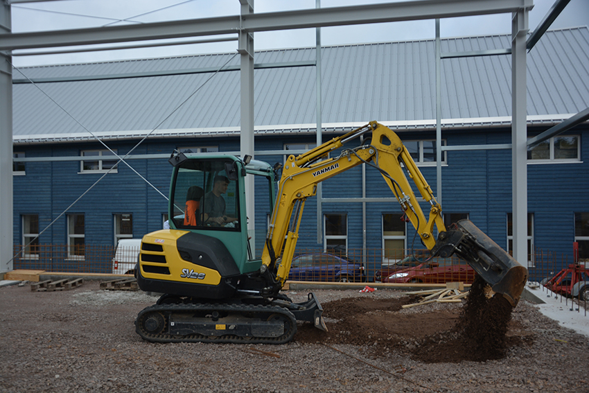 Der Yanmar SV26 verlegt und planiert die Schotterschicht auf dem Fundament. Der Yanmar SV26 verlegt und planiert die Schotterschicht auf dem Fundament.