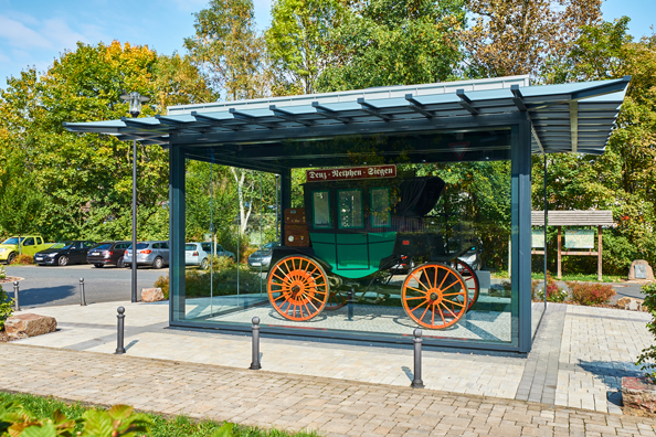 Glaspavillon mit dem Nachbau des ersten Linien-Omnibus vor dem Deuzer Bahnhof. (Bildquelle: alwitra/ Glaspavillon mit dem Nachbau des ersten Linien-Omnibus vor dem Deuzer Bahnhof. (Bildquelle: alwitra/