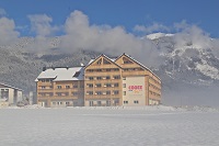 COOEE alpin Hotel Dachstein Außenansicht bei Sonnenschein im Schnee