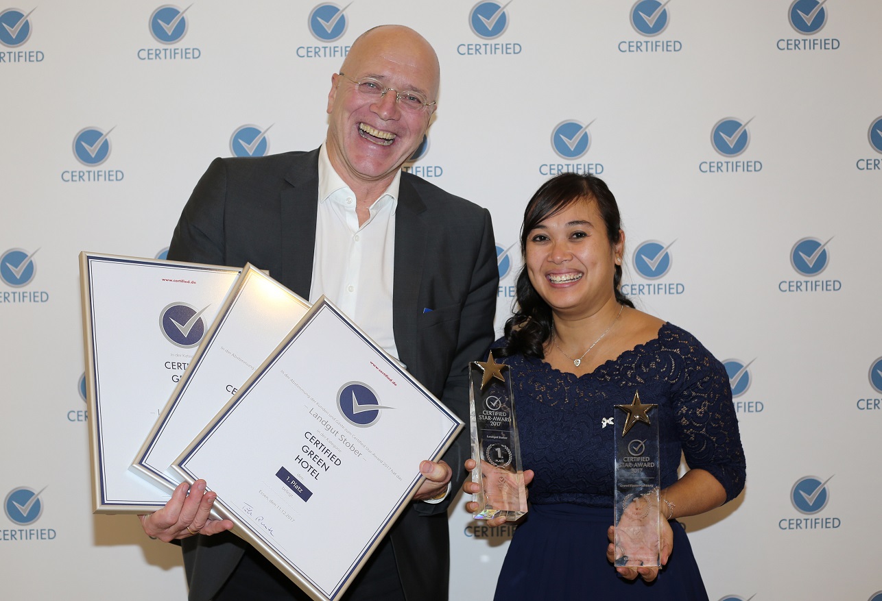 Hotelier Michael Stober erhält seine Auszeichnungen von Certified-Mitarbeiterin Monruedee Hödtke. (B
