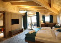 Doppelbett mit Fernseher und Balkon in der Suite (Hotel Gutjahr)