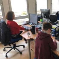 Bild: Kind von DOCUFY-Mitarbeiterin erledigt Hausaufgaben im Büro