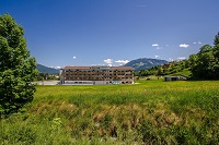 Fassade im Sommer mit Panorama des COOEE alpin Hotels Kitzbühler Alpen (COOEE alpin Hotels)
