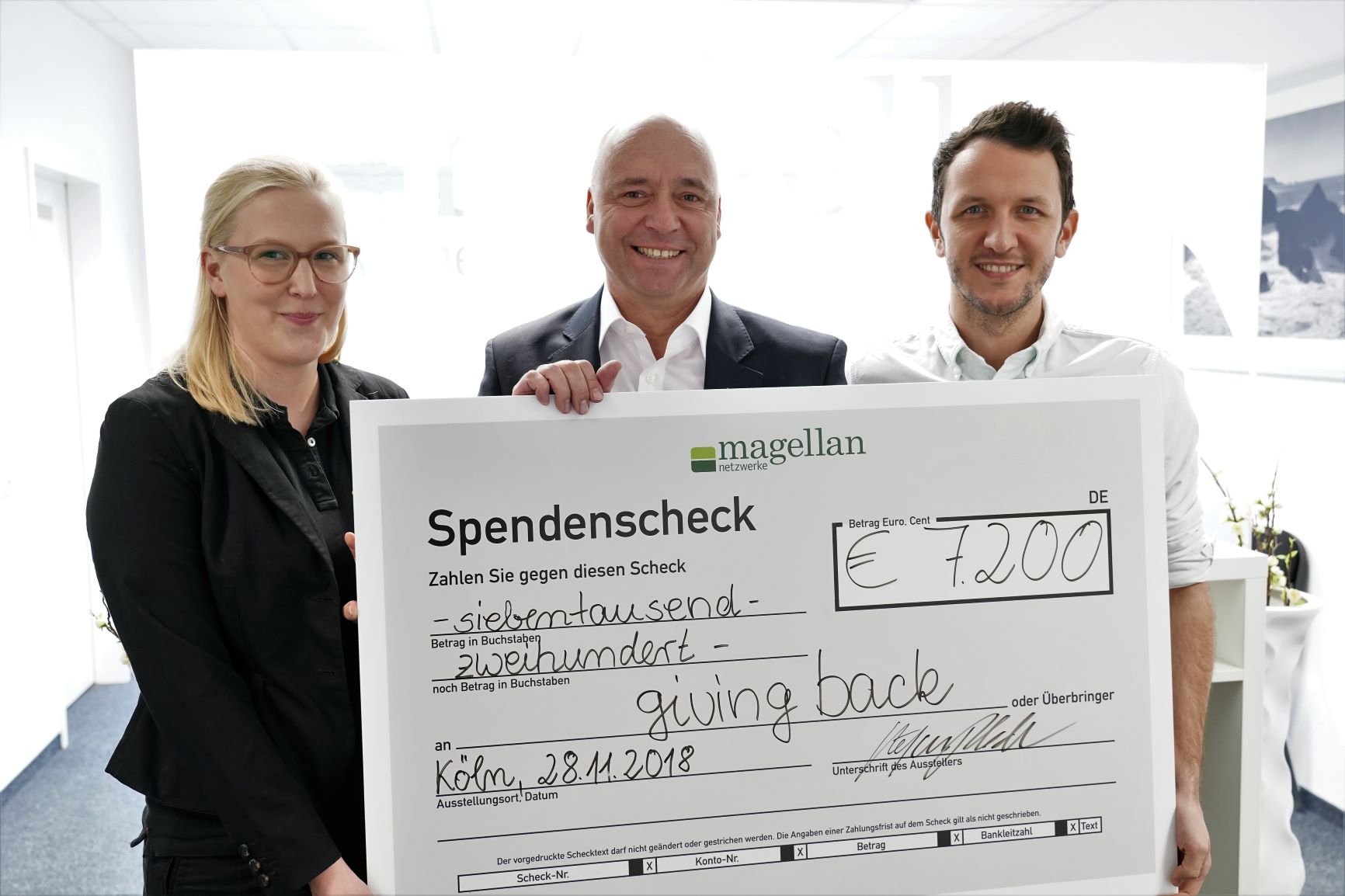 Geschäftsführer Stefan Ploder bei der Scheckübergabe die Stiftungsvertreterinnen von giving back