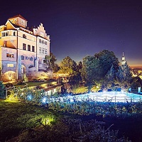 Außenansicht mit beleuchtendem Outdoorpool bei Nacht (Schloss Mönchstein)