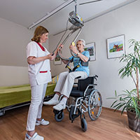 Umhänge-Deckenlifter mit Hebebügel „Helfende Hände“ im Einsatz in einem Altenwohnheim. Umhänge-Deckenlifter mit Hebebügel „Helfende Hände“ im Einsatz in einem Altenwohnheim.