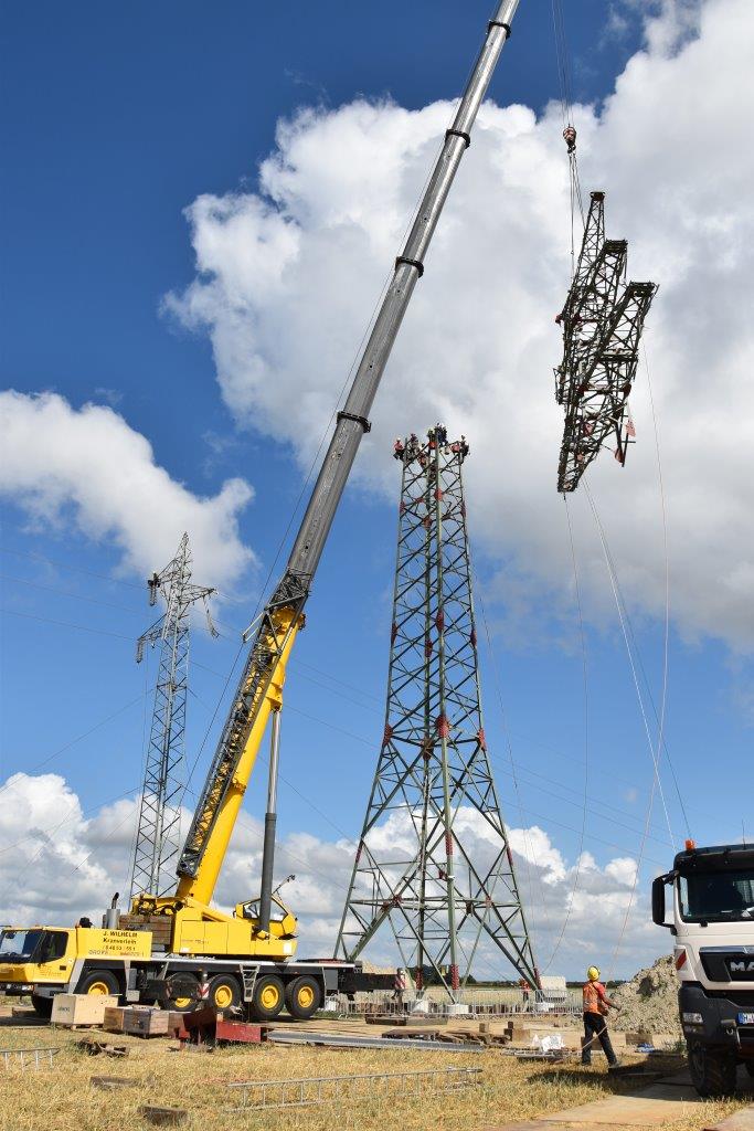 Die Techniker der HanseWerk-Tochter Schlewig-Holstein Netz montieren die Spitze auf den neuen Mast.