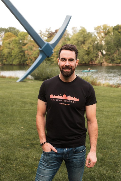 Derek Dinger präsentiert das neue Shirt mit Kassels Skyline und Mundart-Liebesbekenntnis.