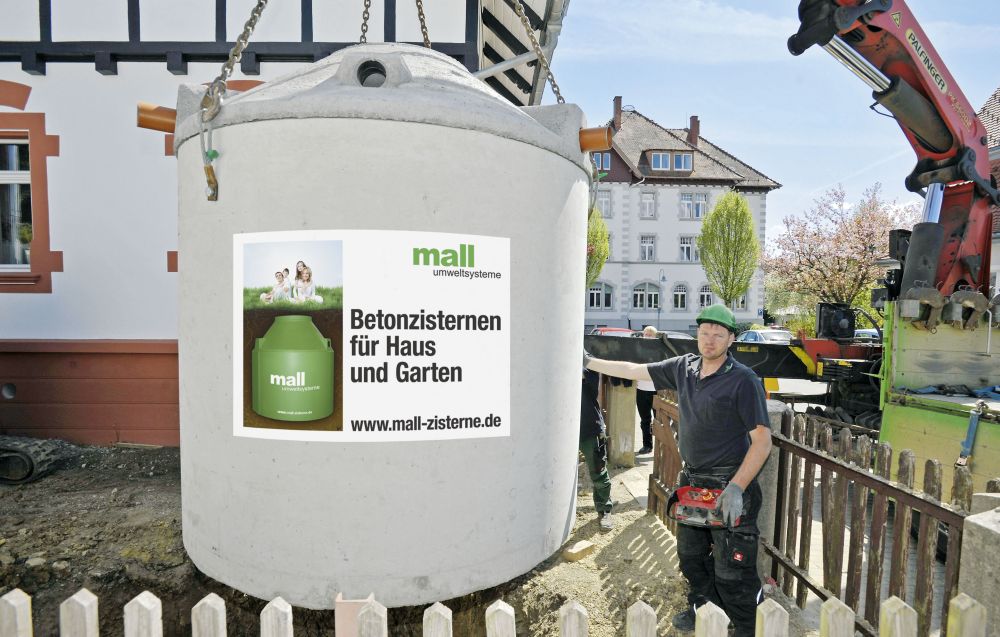 Eine Betonzisterne von Mall wird direkt vom Lieferfahrzeug in die vorbereitete Baugrube versetzt. Eine Betonzisterne von Mall wird direkt vom Lieferfahrzeug in die vorbereitete Baugrube versetzt.