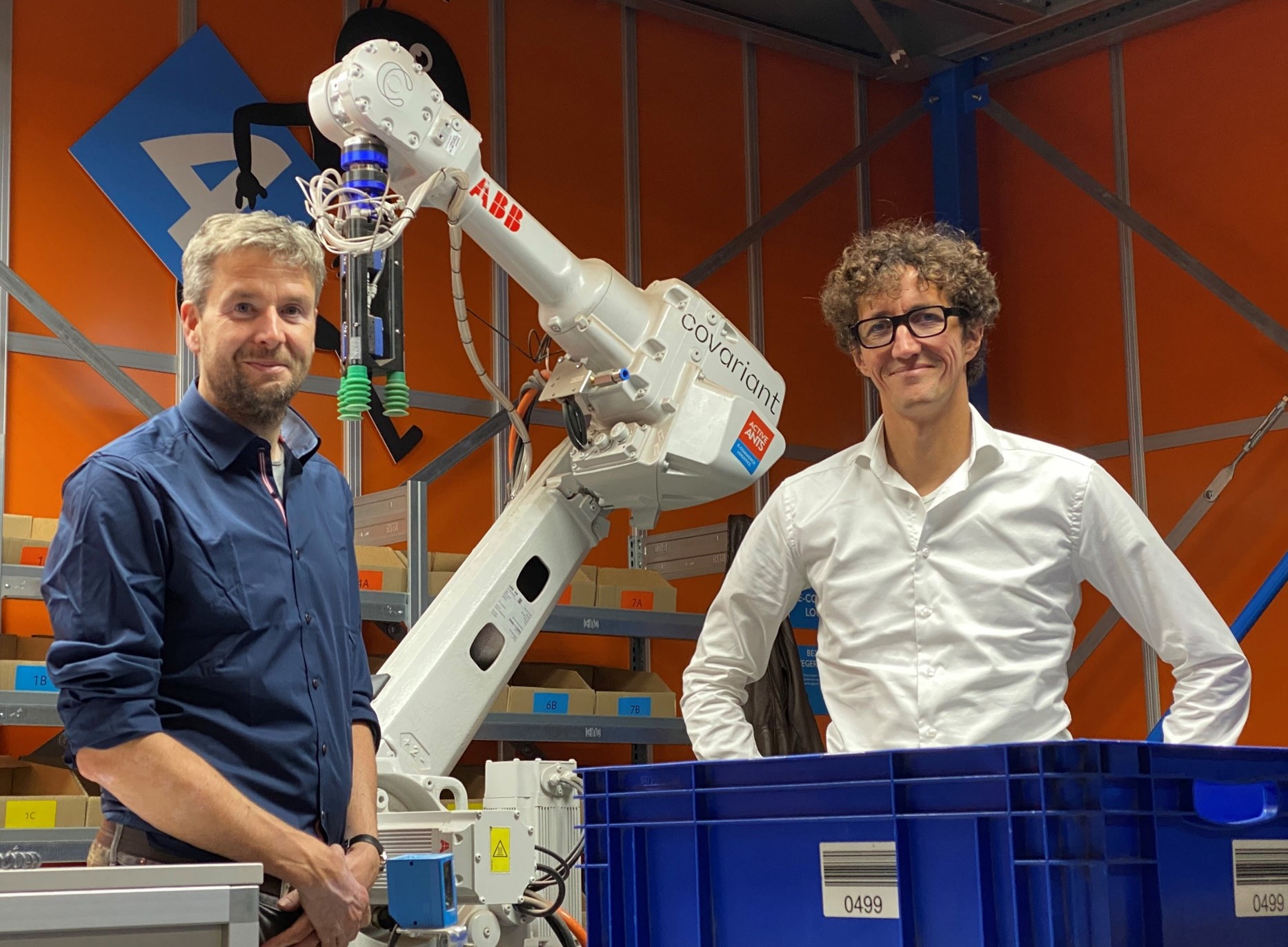 Tobias Wurm und Jeroen Dekker bei einem Roboter der beim Picking für E-Commerce Sendungen Tobias Wurm und Jeroen Dekker bei einem Roboter der beim Picking für E-Commerce Sendungen