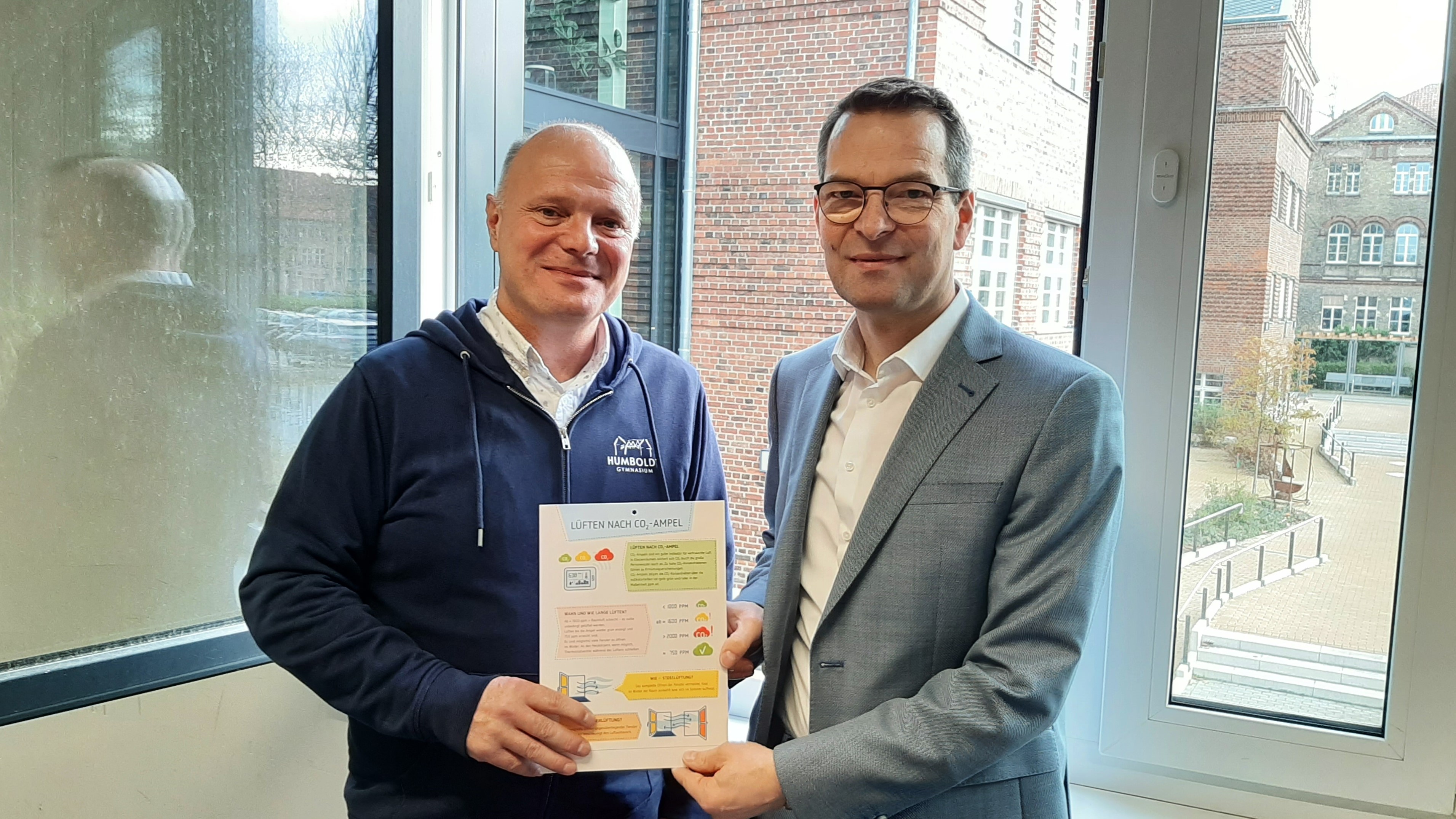 Schulleiter L. Blum (li.) nimmt von WFBB-Geschäftsführer S. Saule einen Aushang entgegen. Foto: WFBB Schulleiter L. Blum (li.) nimmt von WFBB-Geschäftsführer S. Saule einen Aushang entgegen. Foto: WFBB