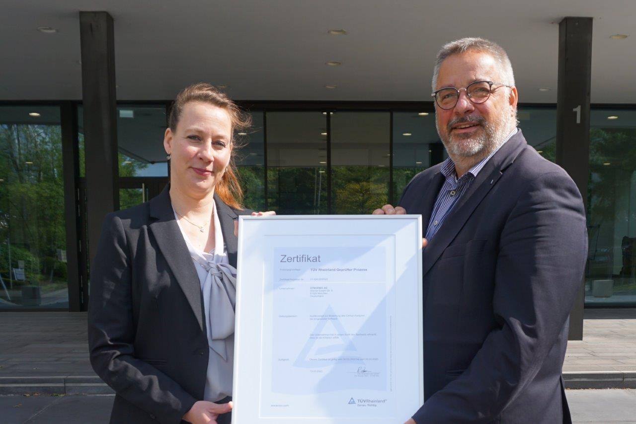 Stephanie Kamp (Syngenio) bekommt das Zertifikat von Olaf Seiche (TÜV Rheinland)überreicht (Bildquelle: Syngenio) Stephanie Kamp (Syngenio) bekommt das Zertifikat von Olaf Seiche (TÜV Rheinland)überreicht (Bildquelle: Syngenio)