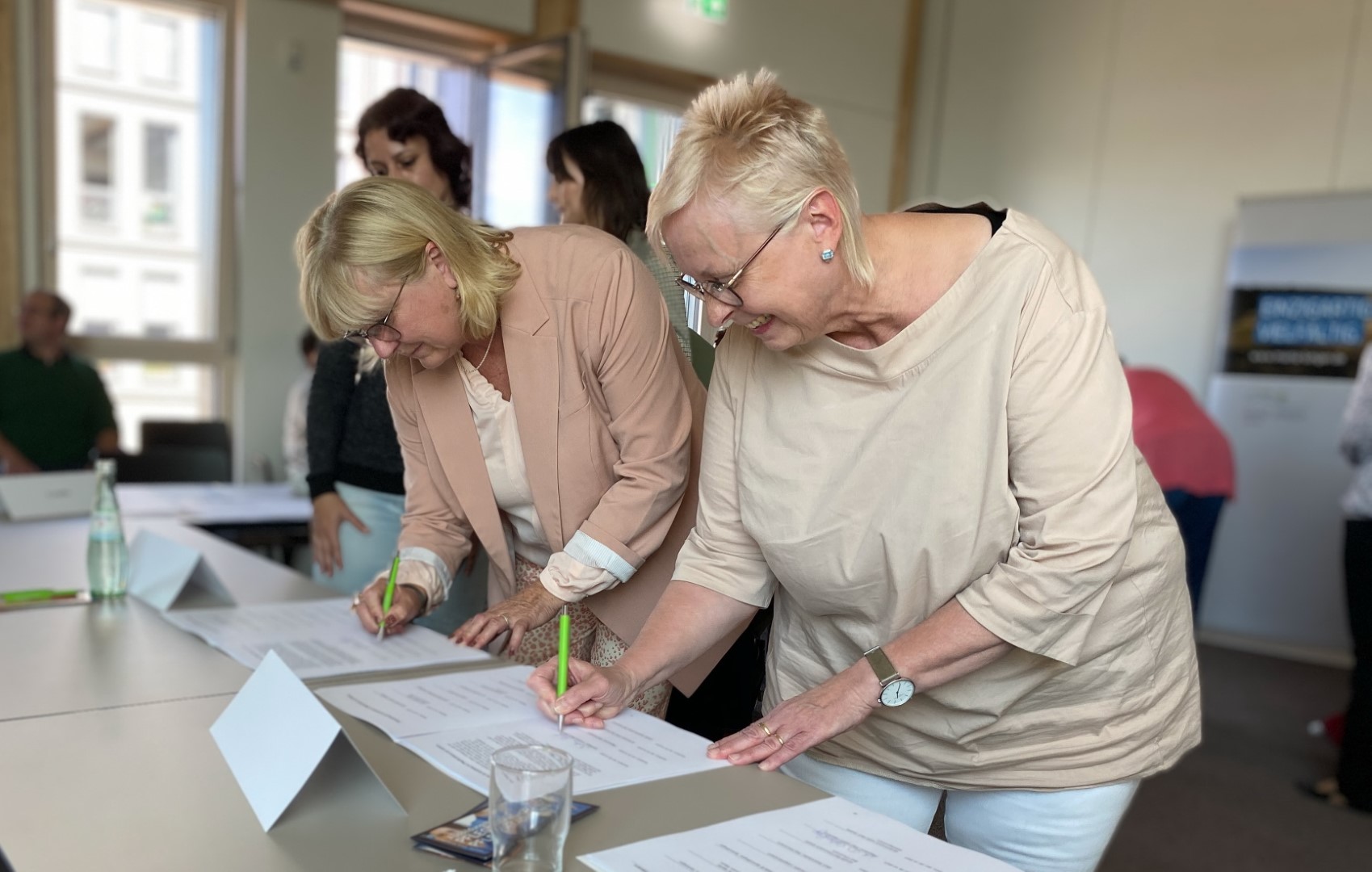 Landrätin Schäfer (rechts) und Birgit Derzbach-Rudolph (links) unterzeichnen Vertrag.