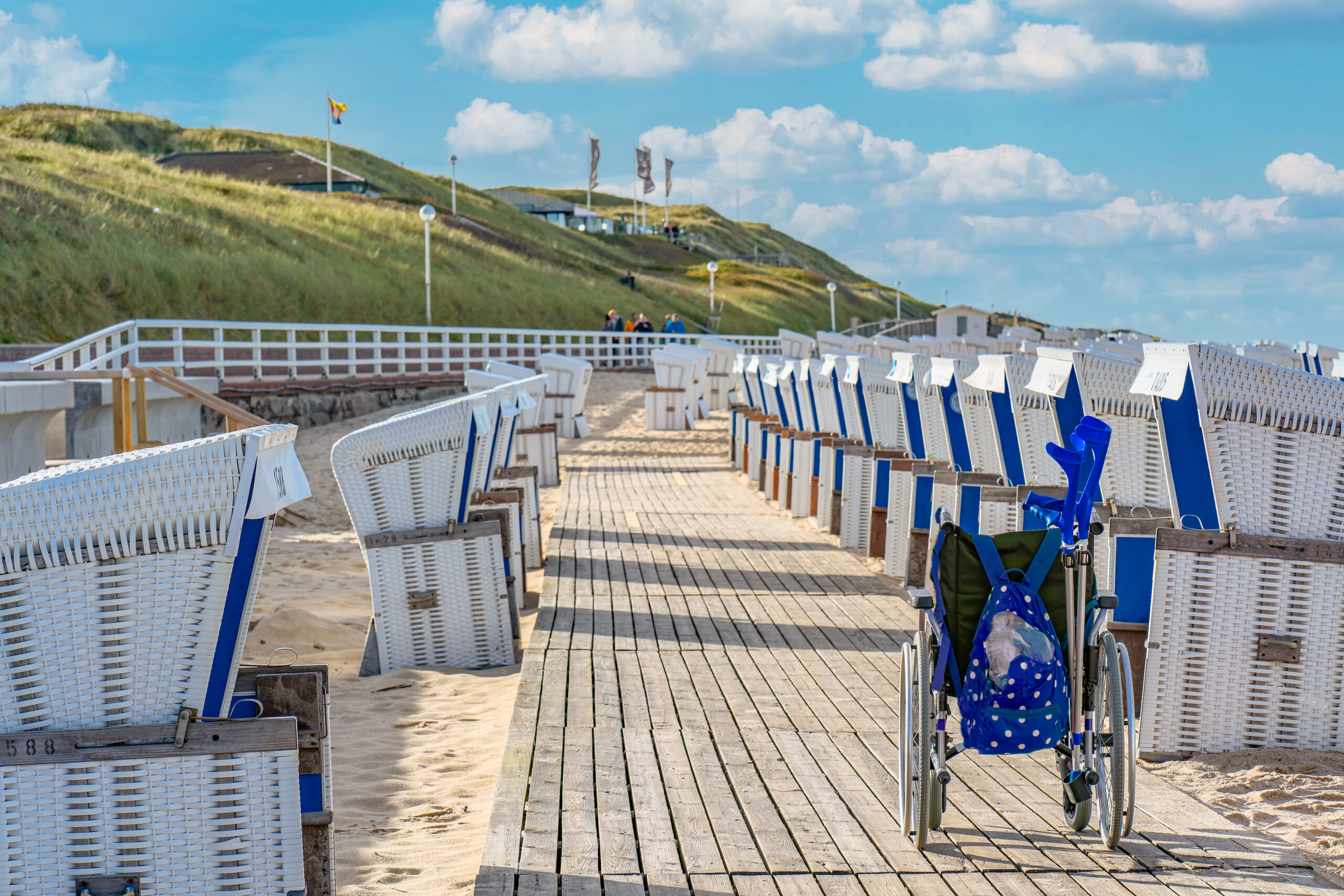 ©Shutterstock - Strand mit Strandkörben und Rollstuhl (Barrierefreiheit wird im Juni Pflicht)