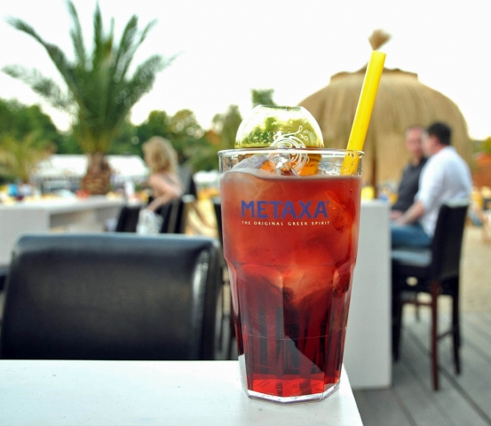 Mit dem leuchtend-roten Sommerdrink METAXA Sunshine ist immer Sommer im Glas, auch wenn die Strandba
